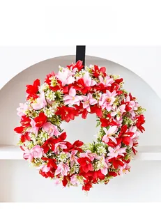 Detail of vibrant faux lily wreath with red and pink blossoms on white backdrop