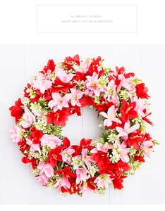 Detailed top view of a lush floral wreath with pink lilies and green leaves on white wood