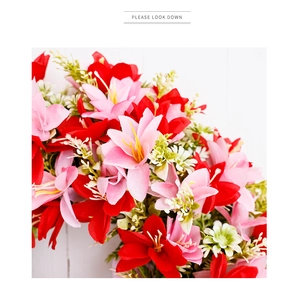 Close-up of vibrant red and pink faux lilies with small white flowers on white wood