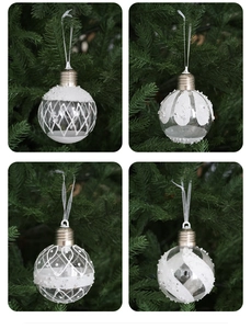 Detail of clear Christmas baubles with white glitter, pearls, and silver caps on tree