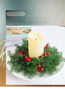 Detail von LED-Kerze mit grünen Tannennadeln und roten Beeren in weißem Tablett