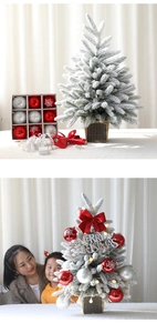 Miniature snow-flocked Christmas tree set with red ornaments and LED star lights