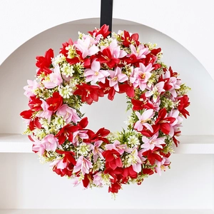 Spring wreath with red and pink artificial lilies, green leaves, and hanging rope for decor