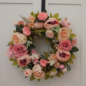Detailed close-up of realistic silk peonies and roses on a rustic floral door wreath