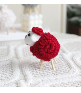 Macro detail of red wool felt sheep ornament with spiral texture on knitted fabric