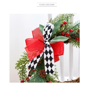 Close-up of Christmas wreath with red berries, pine cones and a burlap bow on white chair