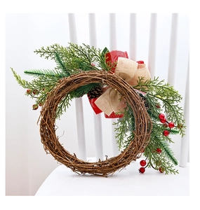 Close-up of Christmas wreath with pine cones, red berries and a rustic burlap bow