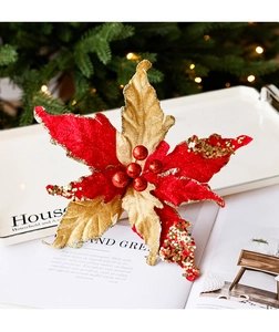 Détail d'une fleur de Noël en velours rouge et paillettes dorées avec baies festives
