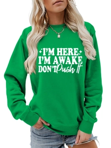 Detail of green sweatshirt with I'M HERE I'M AWAKE white typography and ribbed neck