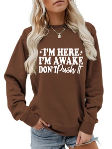 Close-up of the ribbed crewneck and 'I'm Here I'm Awake' white slogan print on brown sweatshirt