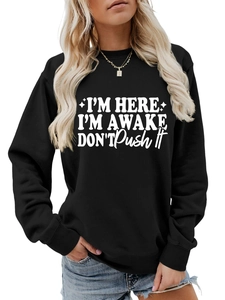 Close-up of text print on black crewneck sweatshirt paired with blue denim jeans