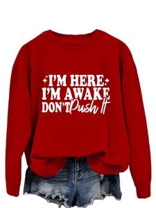 Detail of red crewneck sweatshirt with I'm Here I'm Awake slogan in white artistic font