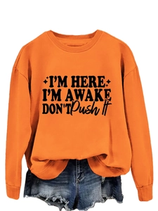 Detail of orange crewneck sweatshirt with black slogan print and ribbed cuffs