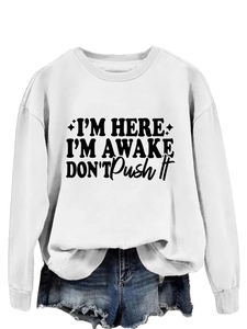 Detail of I'M HERE I'M AWAKE slogan print on white oversized long sleeve sweatshirt