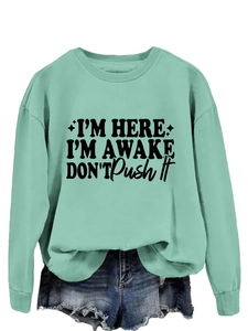Detail of mint green sweatshirt with I'm Here slogan and distressed denim shorts