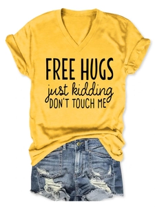Flat lay of yellow V-neck T-shirt featuring Free Hugs Just Kidding humor slogan