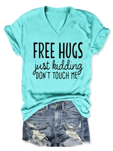 Flat lay of a mint green V-neck t-shirt with 'Free Hugs' print and ripped denim shorts