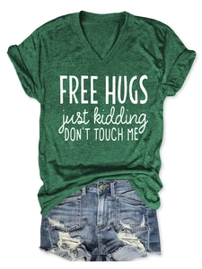 Flat lay of a green V-neck T-shirt with humorous slogan and distressed denim shorts