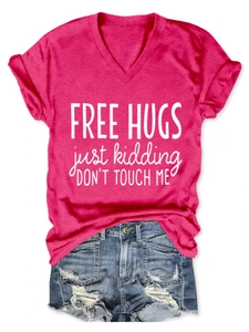 Detail of rose red V-neck T-shirt with 'Free Hugs' print and distressed denim shorts