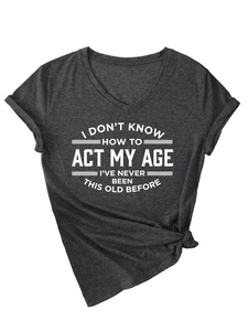 Detalle de camiseta gris con cuello en V, estampado 'ACT MY AGE' y dobladillo anudado