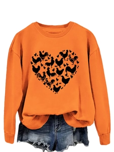 Detail of orange sweatshirt featuring a black heart-shaped chicken pattern and denim shorts