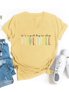 Dettaglio della t-shirt con scollo a V, nodo laterale e stampa pickleball su fondo giallo