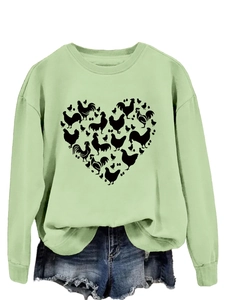 Macro detail of heart-shaped chicken and egg print on light green sweatshirt fabric