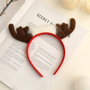 Détail d'un serre-tête de Noël avec bois de renne et pompons posé sur un livre
