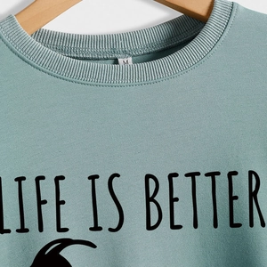 Light green crewneck sweatshirt with LIFE IS BETTER print on wooden hanger size M