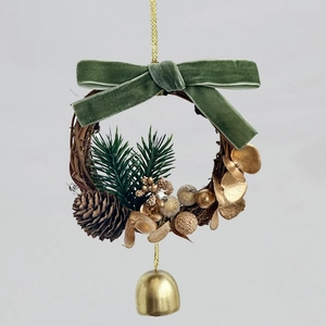Detail of Christmas wreath with golden bell, pine cones, and green velvet bow ornament