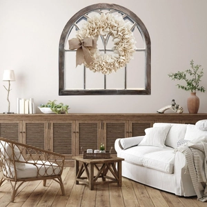 Rustic beige burlap wreath with large bow hanging on a vintage wooden arched window frame