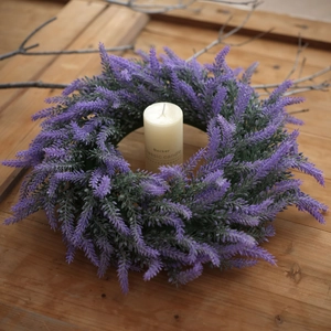 Detail of a purple lavender wreath with realistic green leaves and a pillar candle