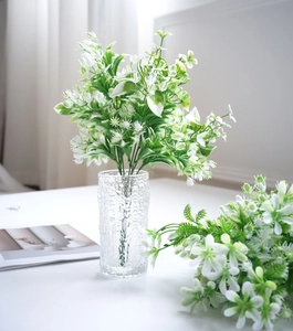 Close-up of artificial jasmine plant in a textured glass vase with ice-crack patterns