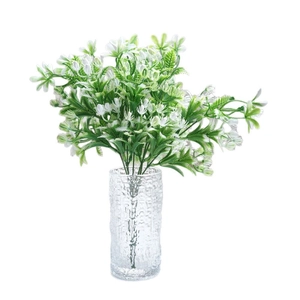 Artificial green jasmine bouquet in a textured clear glass vase for desktop decoration