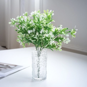 Artificial white jasmine flowers in a textured hammer glass vase for desk decor
