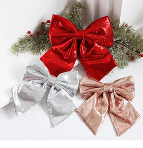 Close-up of sparkling sequined Christmas bows in red, silver, and rose gold on pine branches