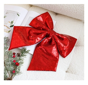 Close-up of red sequined Christmas bow on white faux fur with pine cone and berries