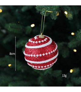 Detail of an 8cm red glitter Christmas ball with white lace and pearls on a tree branch