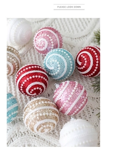 Detail of 8cm glitter Christmas foam balls with spiral pearl texture on a white knit blanket