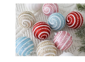 Close-up of glitter Christmas foam balls with pearl swirls on a cozy white knit blanket