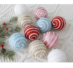 Detail of glittery Christmas balls with pearl spiral patterns on a cozy white knit blanket