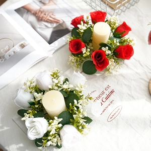 Portavelas de corona de rosas artificiales con flores rojas y hojas de eucalipto en mesa