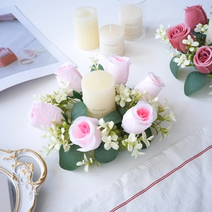 Detalle de corona portavelas con rosas de seda rosa y vela de pilar blanca clásica