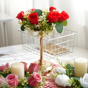 Detalle de candelabro de metal dorado con rosas rojas y flores blancas de acento