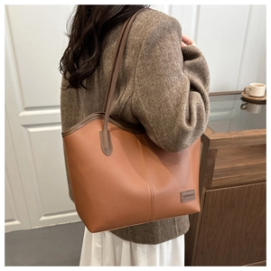 Detail of brown litchi pattern tote bag with leather tag and shoulder strap on model