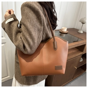 Close-up of brown leather tote bag with vertical stitching and FASHION & BAGS label