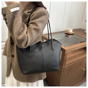 Close-up of a black lychee texture leather tote bag featuring a leather logo patch