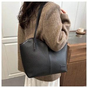 Detailed side view of a large black lychee leather tote bag worn by a model