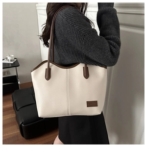 Close-up of off-white pebble leather tote bag with brown trim and fashion logo plate
