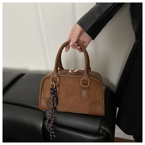 Dettaglio borsa Boston marrone con manici dorati e ciondolo in corda intrecciata